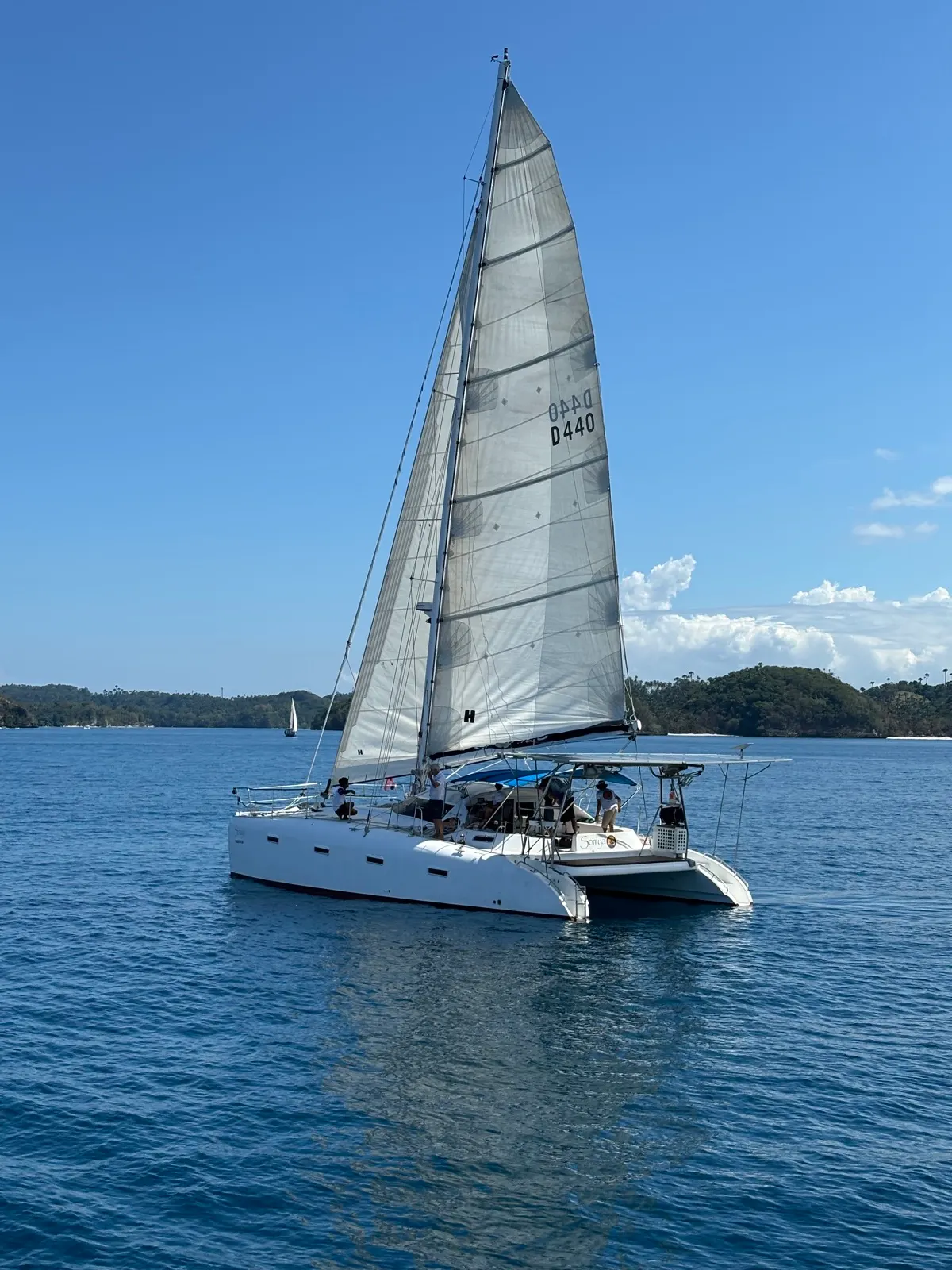 Soniya under sail with island mountains behind