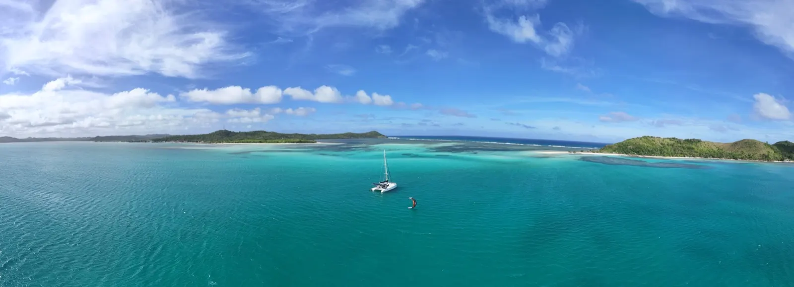 Soniya sailing through a wide calm bay flanked by green hills