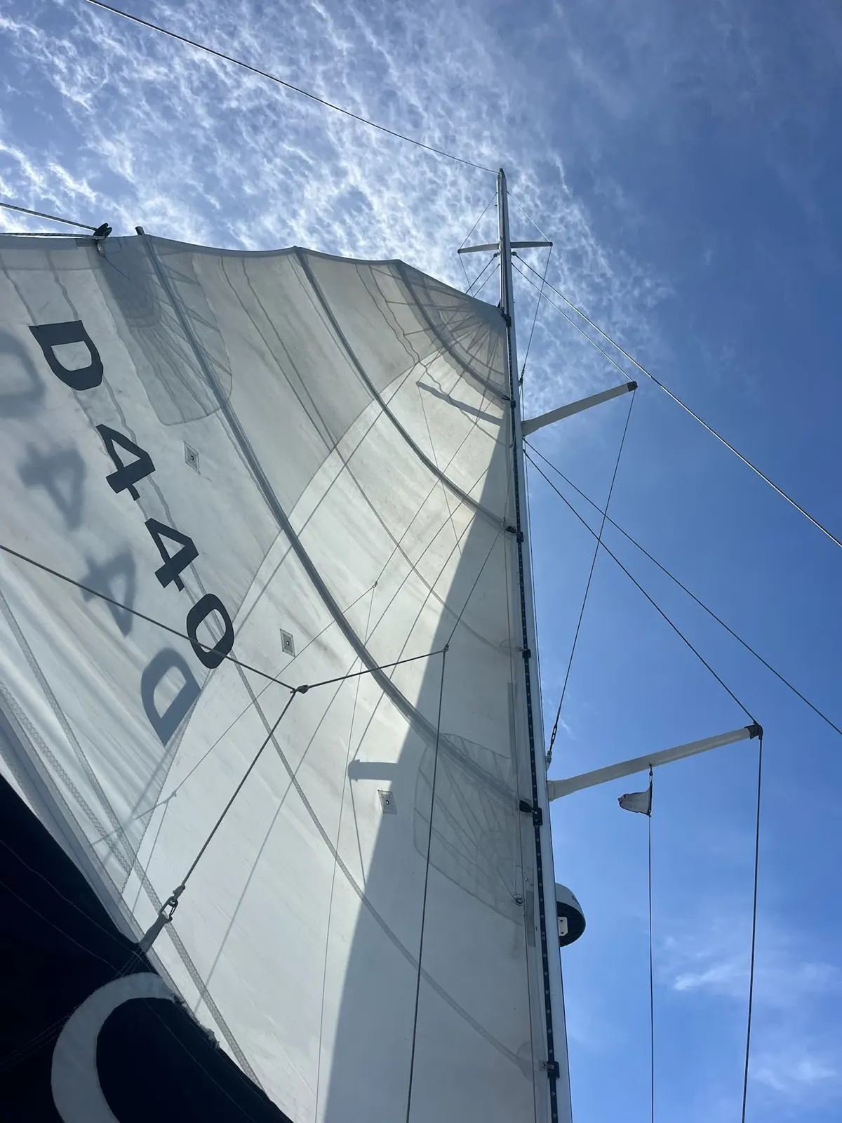 Looking up at mainsail and rigging against clouds