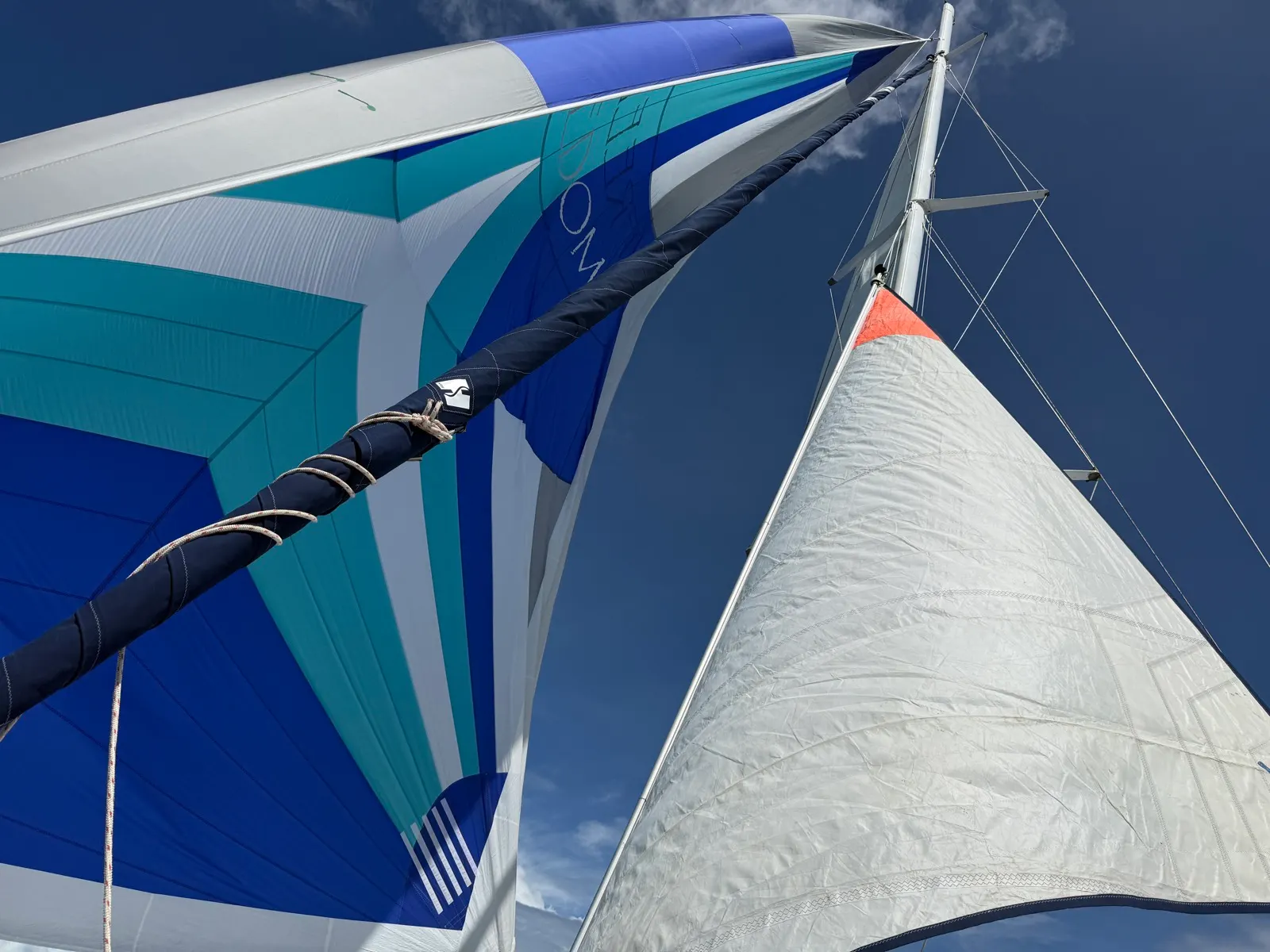Colorful spinnaker and mainsail against blue sky