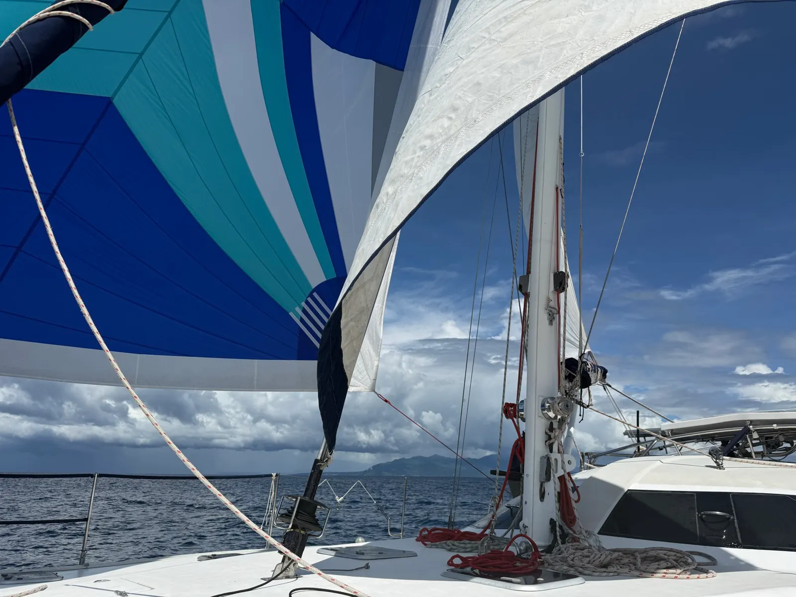 Blue spinnaker and sails against cloudy sky