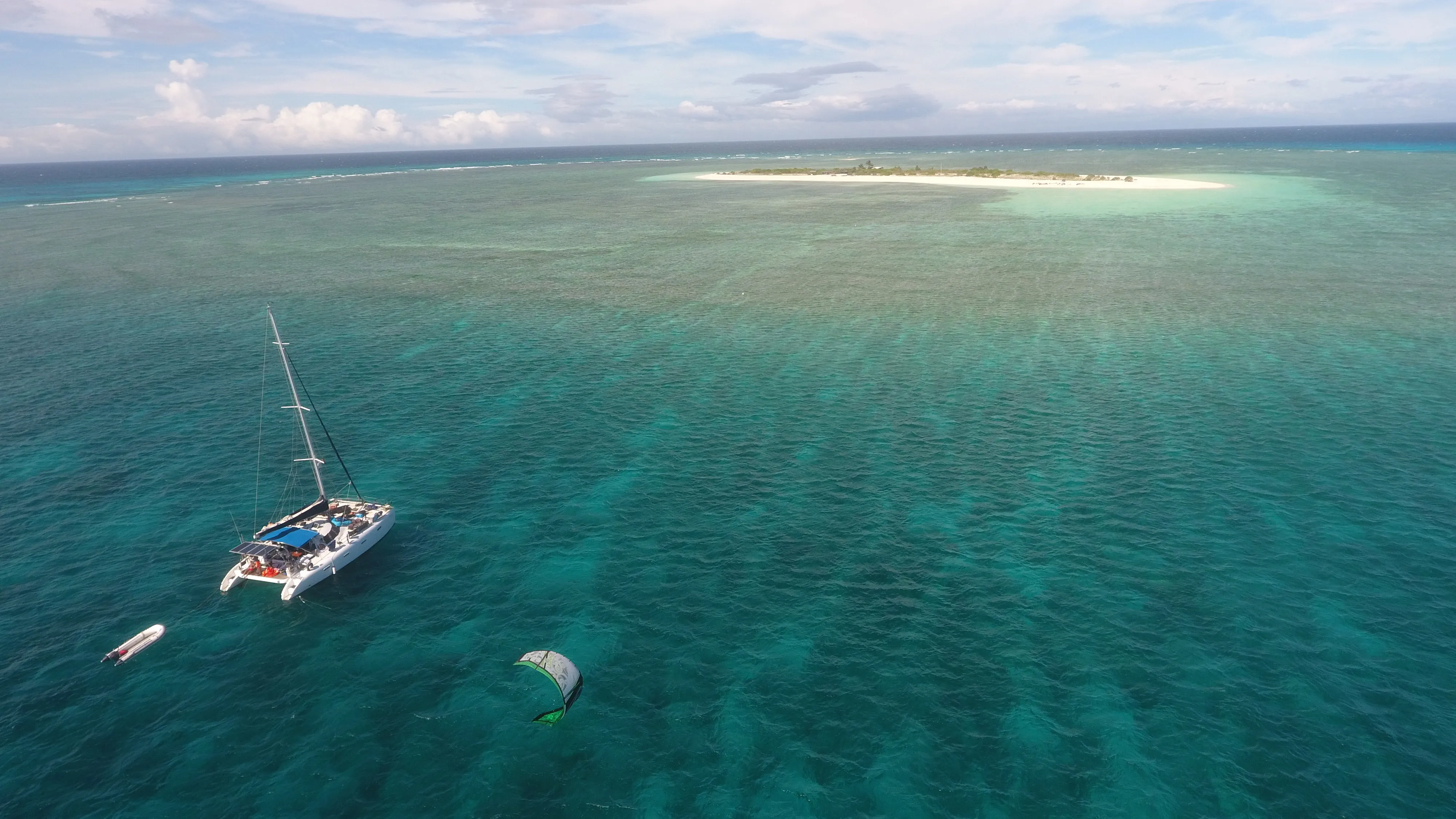 Wide aerial of Soniya anchored near Seco Island with a kitesurfer