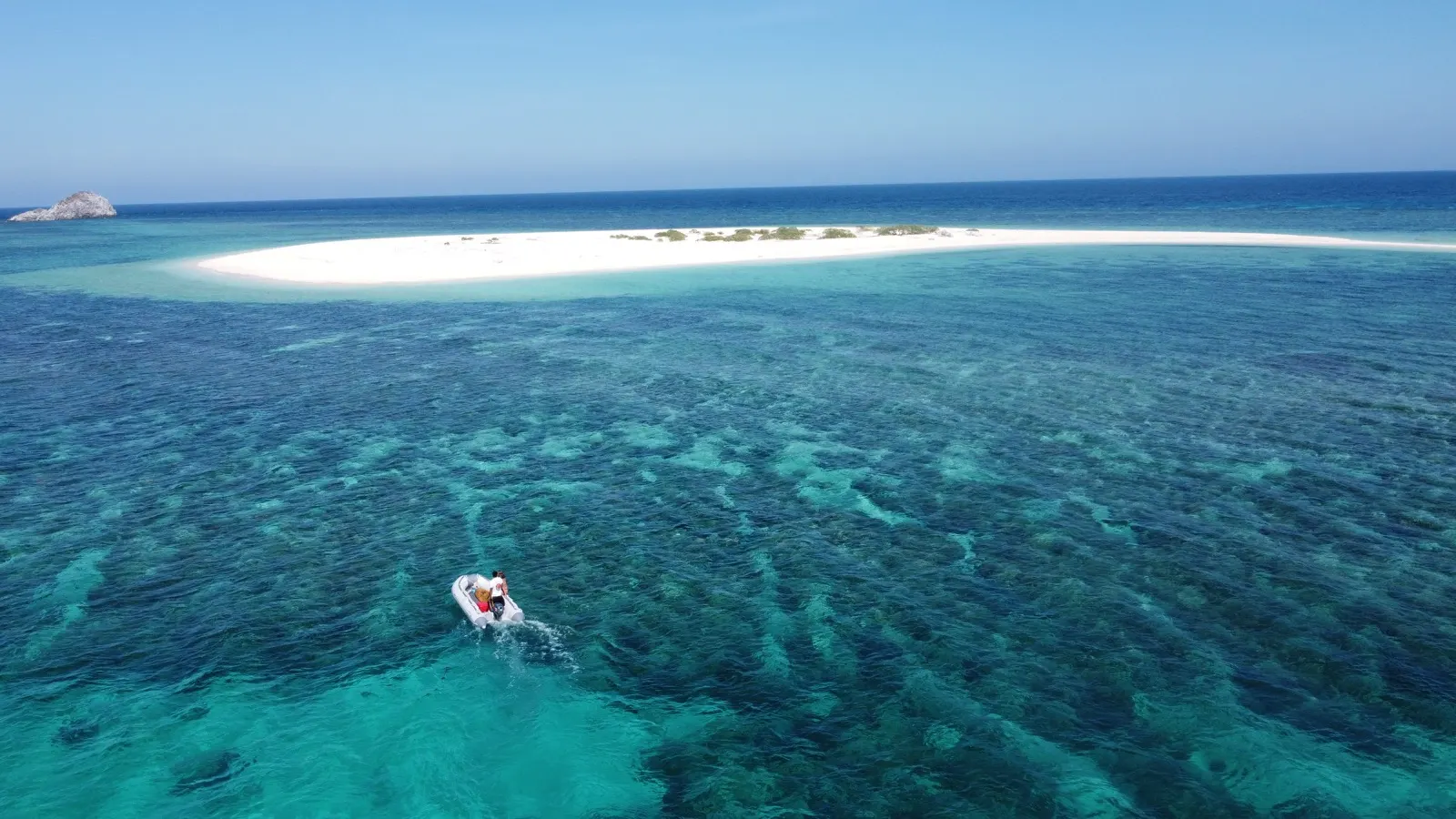 Dinghy approaching sandbar, wider view with distant rock