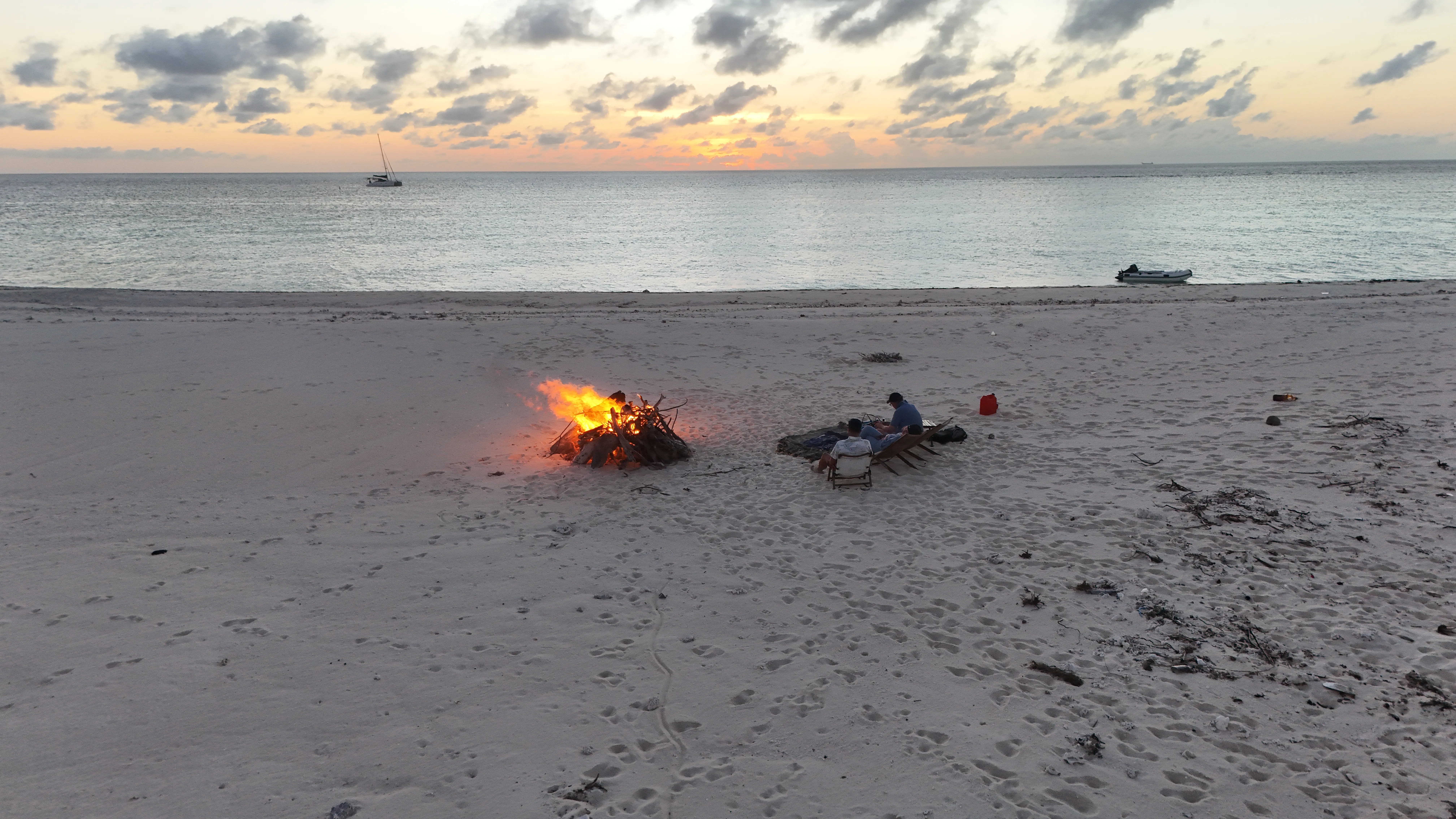Beach bonfire at sunset on Seco Island with Soniya anchored offshore