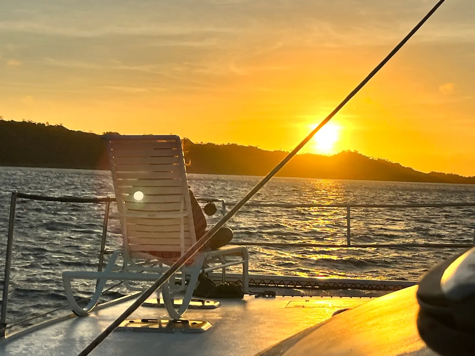 Empty deck chair silhouetted against sunset