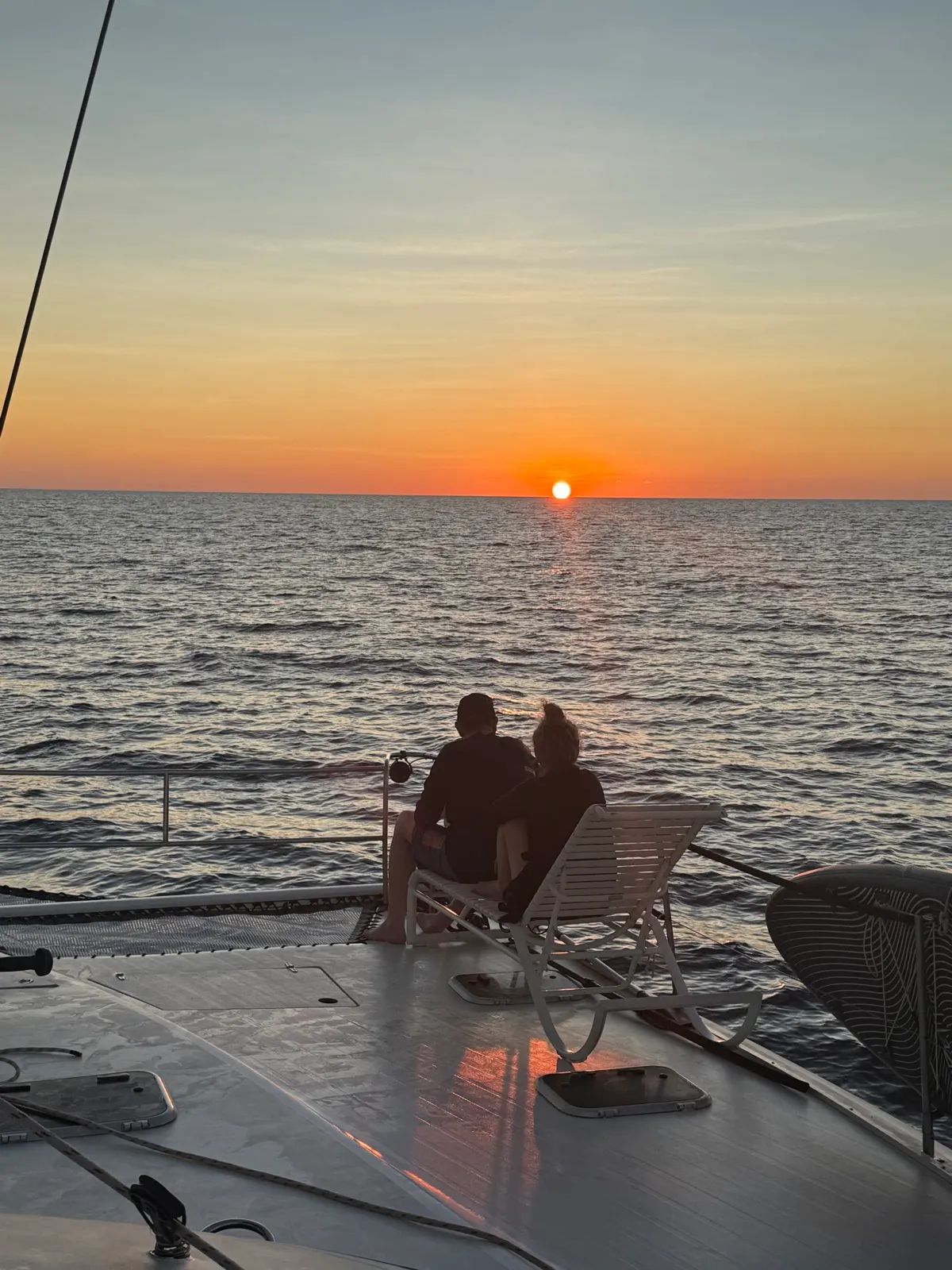 Two people sitting on deck watching sunset