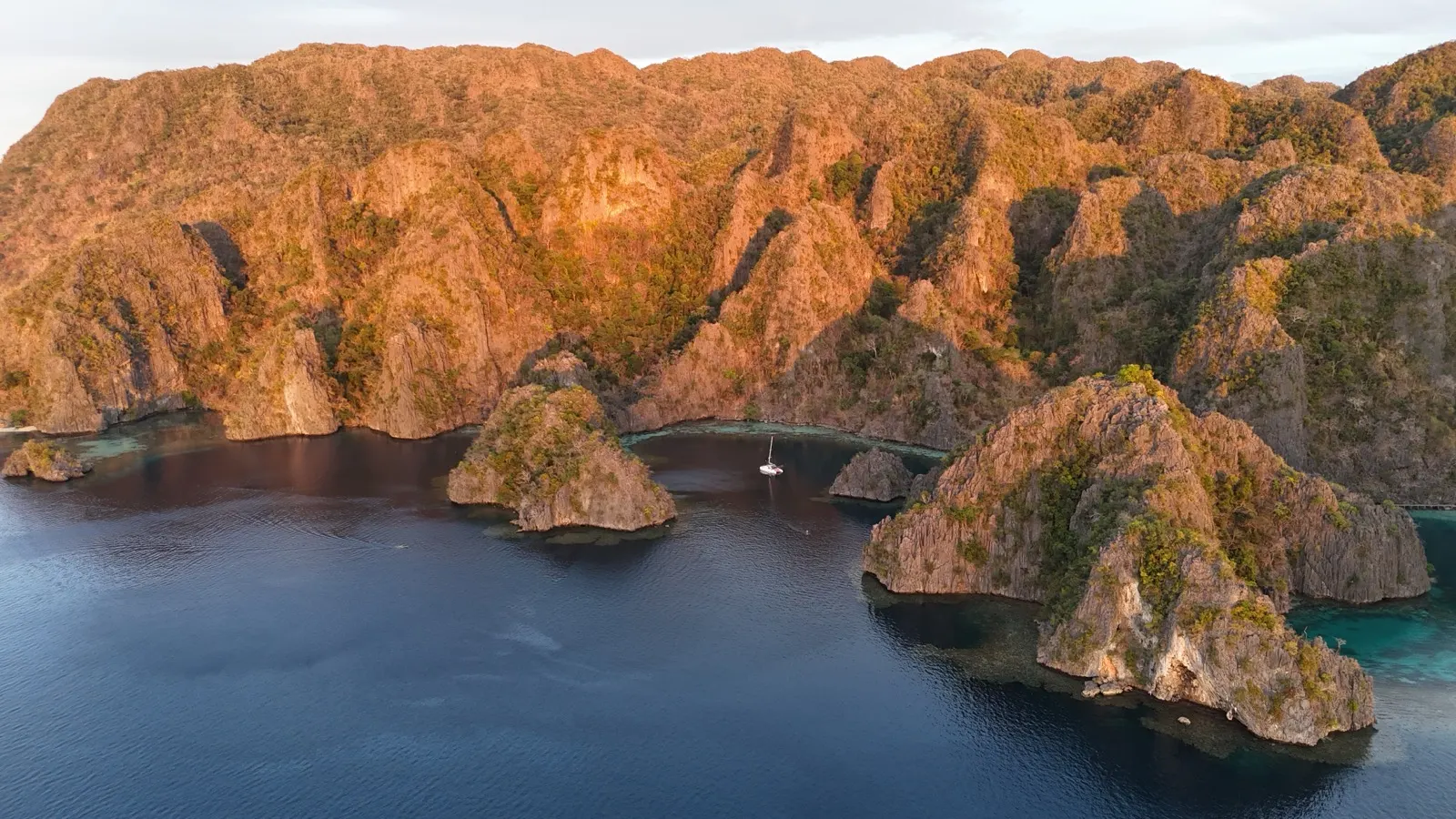 Sunset panorama of cliffs, lagoon, and catamaran